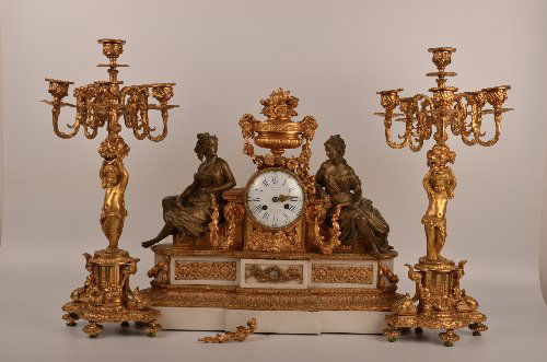 Three piece French gilt bronze and marble figural clock: A three piece French gilt bronze and marble figural clock garniture set, the clock topped with a floral urn and flanked by classical beauties, raised on a marble and gilt bronze mounted base, accompan