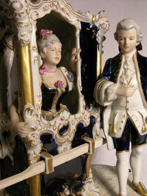 Royal Dux grouping of two attendants with one elegant: Royal Dux grouping of two attendants with one elegant lady in her sedan carriage. Properly stamped "Royal Dux" with raised pink triangle. Height 13".