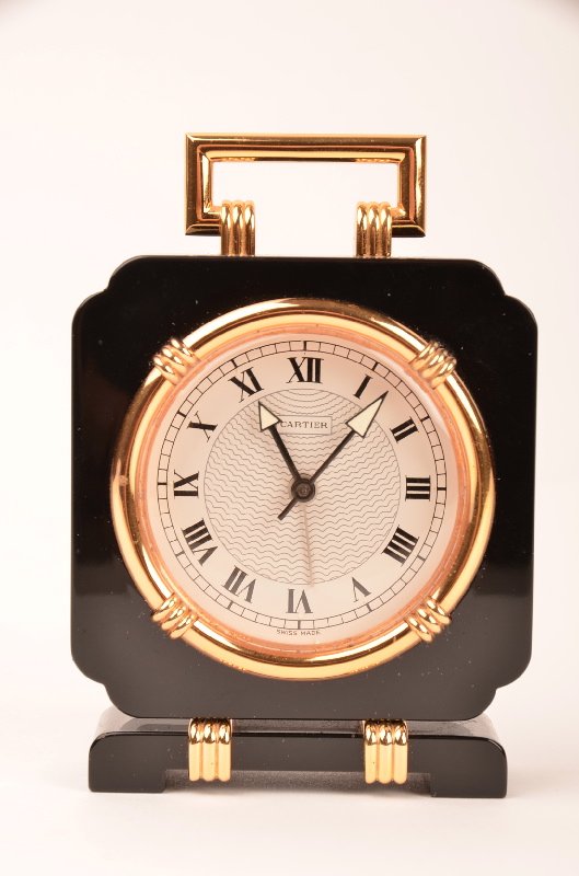Cartier small desk clock model number 901701565.: Cartier small desk clock model number 901701565.In a black polished marble frame.Painted Roman Numerals around the face.Overall height 4 1/4 inches.