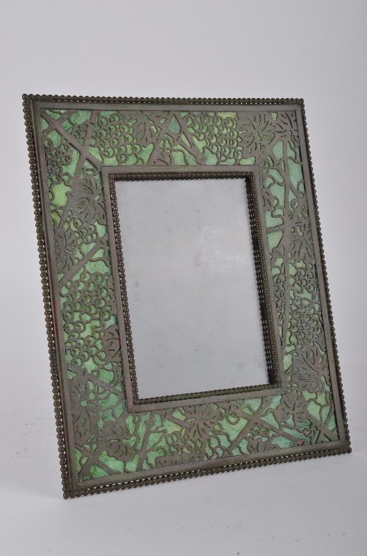 Tiffany Studios "Grapevine" photo frame with green: Tiffany Studios "Grapevine" photo frame with green glass. Stamped Tiffany Studios New York 947. Holds a 4 inch x 5 1/2 inch photo. Ovwerall size of frame 8 inches x 9 1/2 inches.