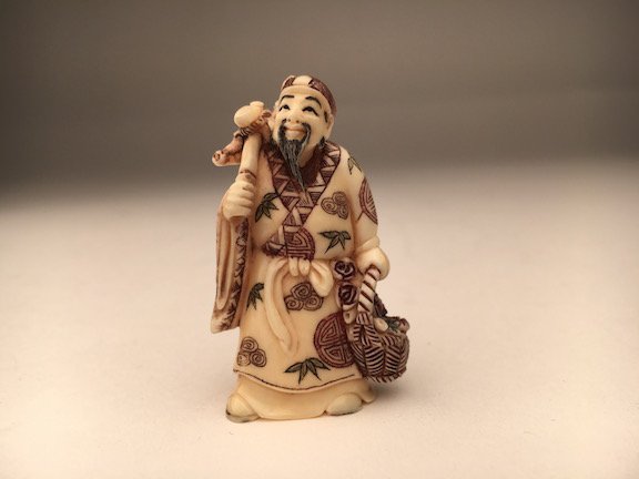 A carved Netsuke figure of a man with a basket (1 of 3)