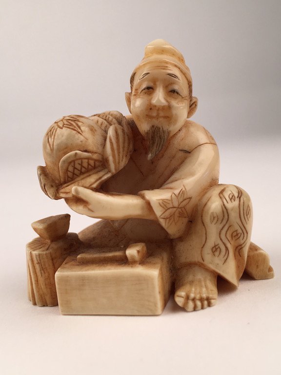 Carved Netsuke figure of a seated man with a hammer. (1 of 4)