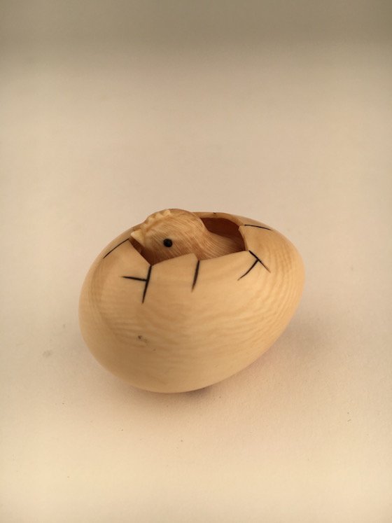 A carved Netsuke figure of a small chick cracking his (1 of 3)