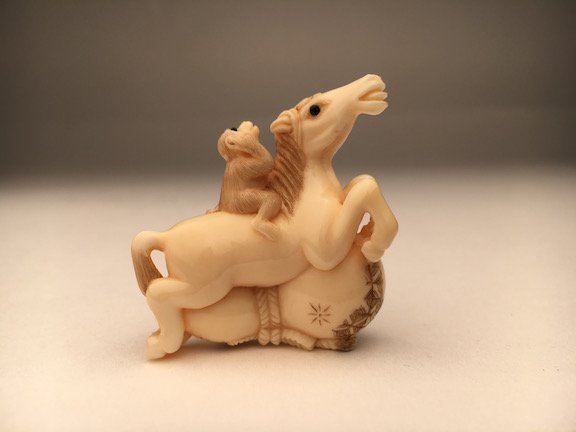 A carved Netsuke horse with a monkey. (1 of 3)