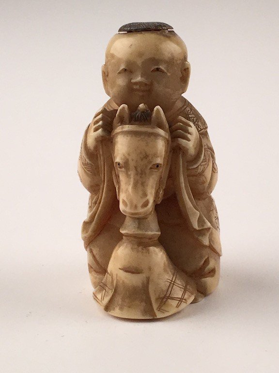 Carved Japanese Netsuke figure of a young child riding (1 of 5)