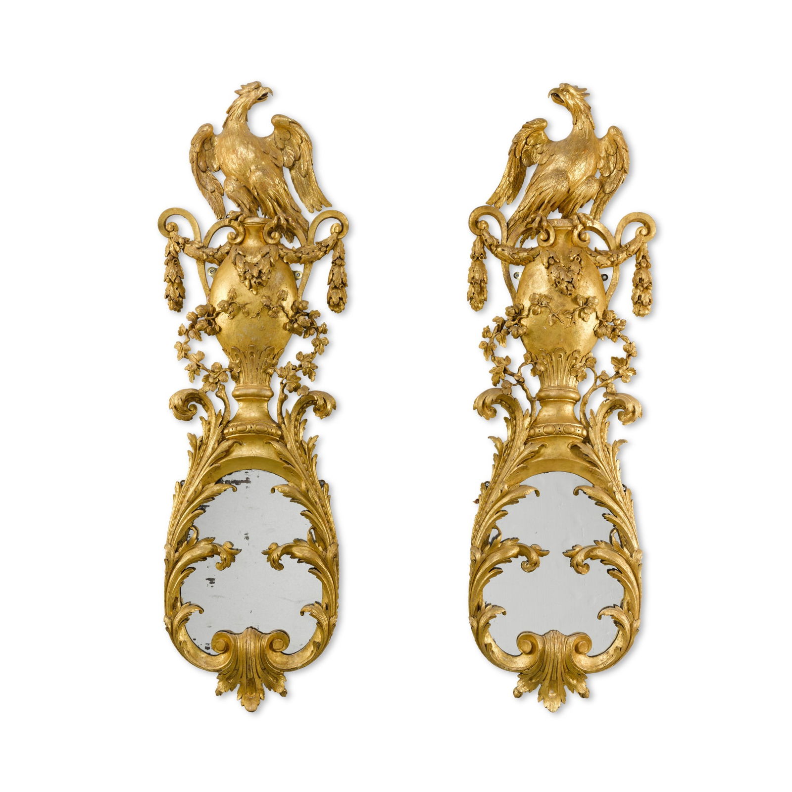 A pair of George II carved giltwood girandole wall mirrors, circa 1740, in the manner of William: A pair of George II carved giltwood girandole wall mirrors, circa 1740, in the manner of William Kent each oval mirror plate within a foliate-carved frame surmounted by a cresting with a displayed eag