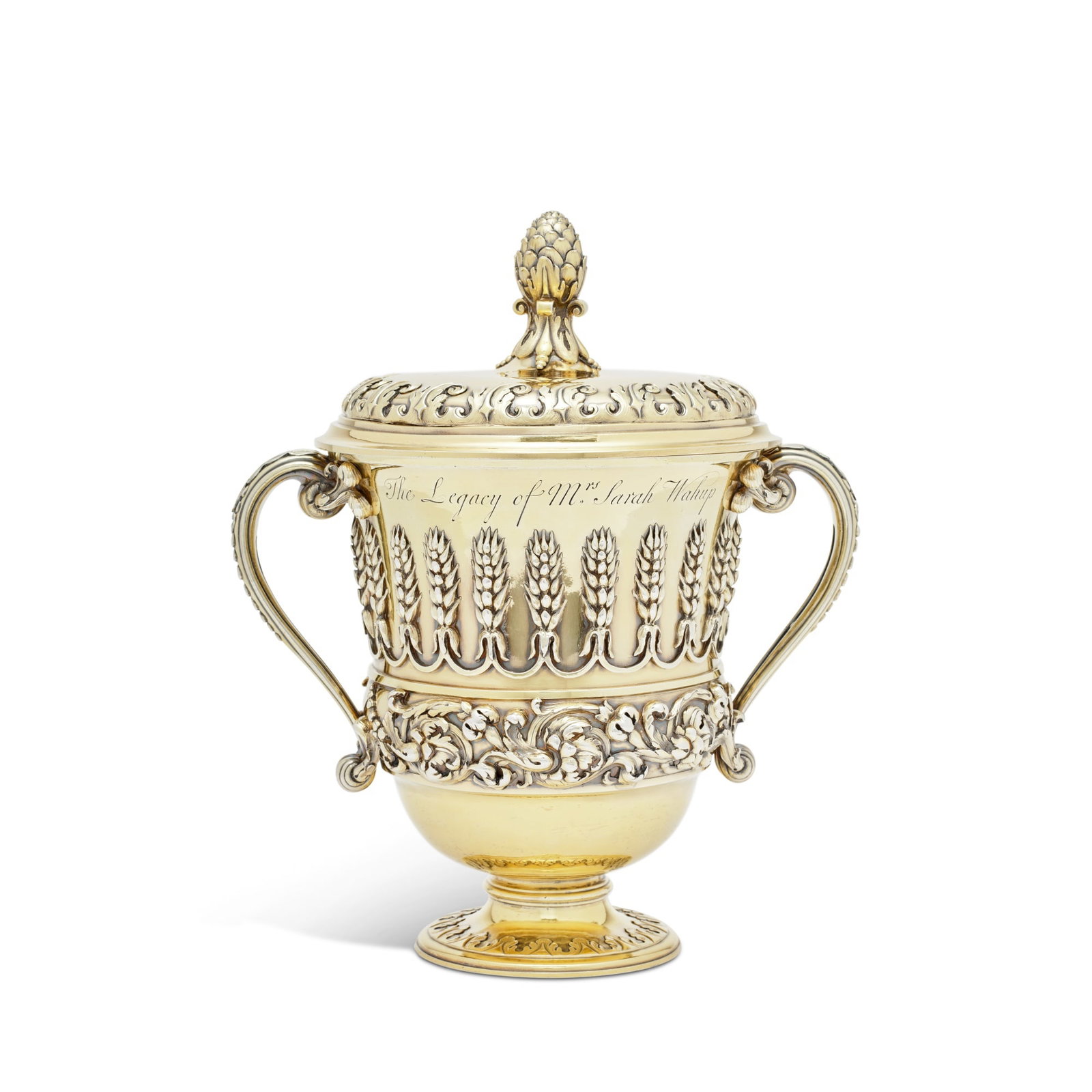 The Wahup Cup, A George II Silver-Gilt Cup And Cover, After Designs By William Kent, Elizabeth: campana form, the neck applied with ears of wheat above a band of intertwining foliage, the foot with acanthus leaf ornament, the body with two acanthus-leaf capped handles, the cover with a pine cone