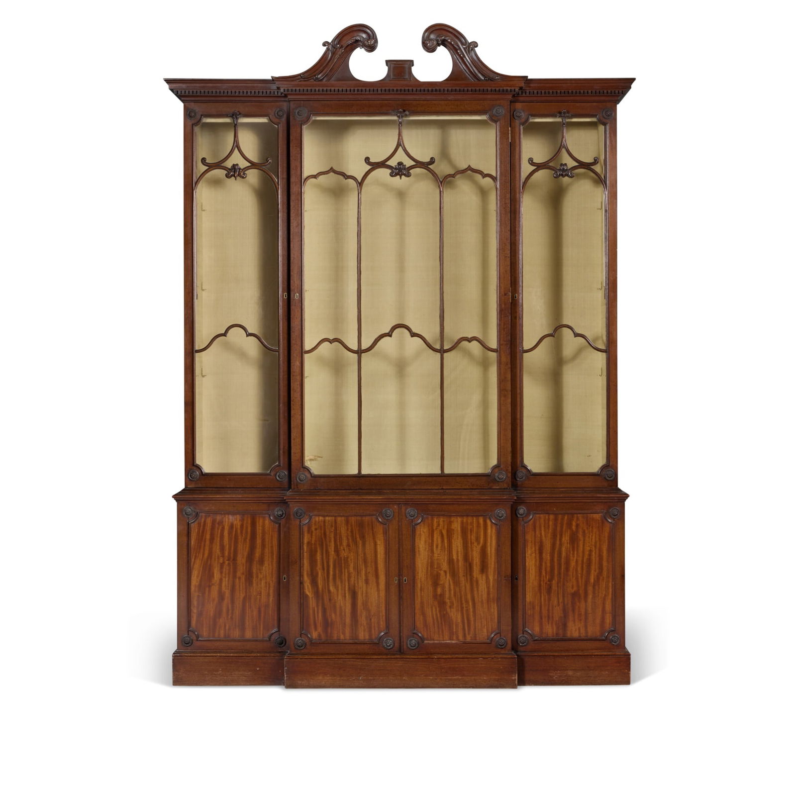 A George III Mahogany Breakfront Bookcase in the manner of Thomas Chippendale, Circa 1775: Property from a Westchester, New York Collection (lots 61-67) The upper cabinet interiors now lined in pale yellow silk with glass shelves and wired for lighting height 100 ½ in.; width 70 ¼