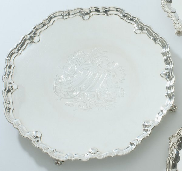 A George II silver large salver, Robert Peaston, L: A George II silver large salver, Robert Peaston, London 1735 with 'Chippendale' rim, the center engraved with arms in lozenge within shellwork and strap cartouche flanked by sprays of reeds and coral,