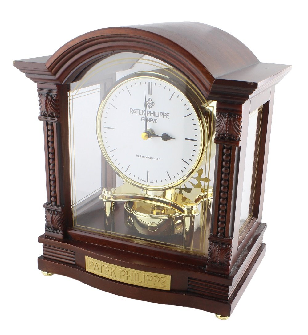 A PATEK PHILIPPE HORIZONTAL PENDULUM DEALERS CLOCK: A PATEK PHILIPPE HORIZONTAL PENDULUM DEALERS CLOCK CIRCA 1990s D: White dial with applied markers. M: A chiming Quartz movement with rotating pendulum. C: A rich walnut finish wooden case, measures ap