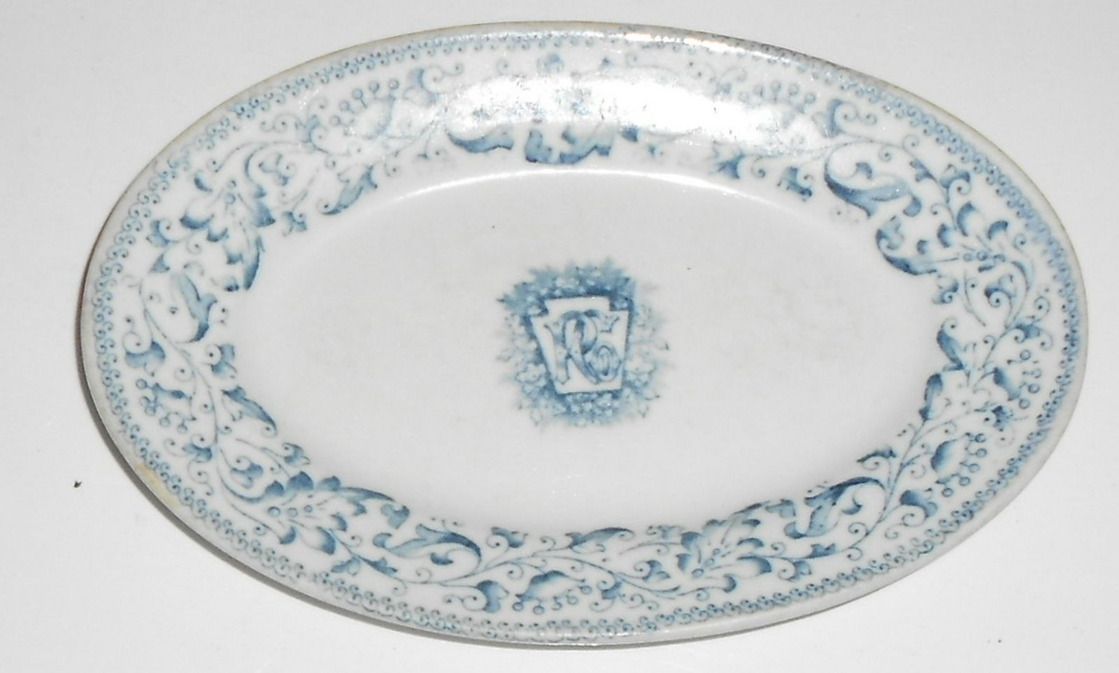 Pennsylvania Railroad "Pittsburgh" Platter: China platter made by KT&K for the Pennsylvanian Railroad in their "Pittsburgh" pattern. It measures 7" by 4 1/2". Nice heavy ware with logo in th3e center. Reverse has eth KT&K English logo. Clean.