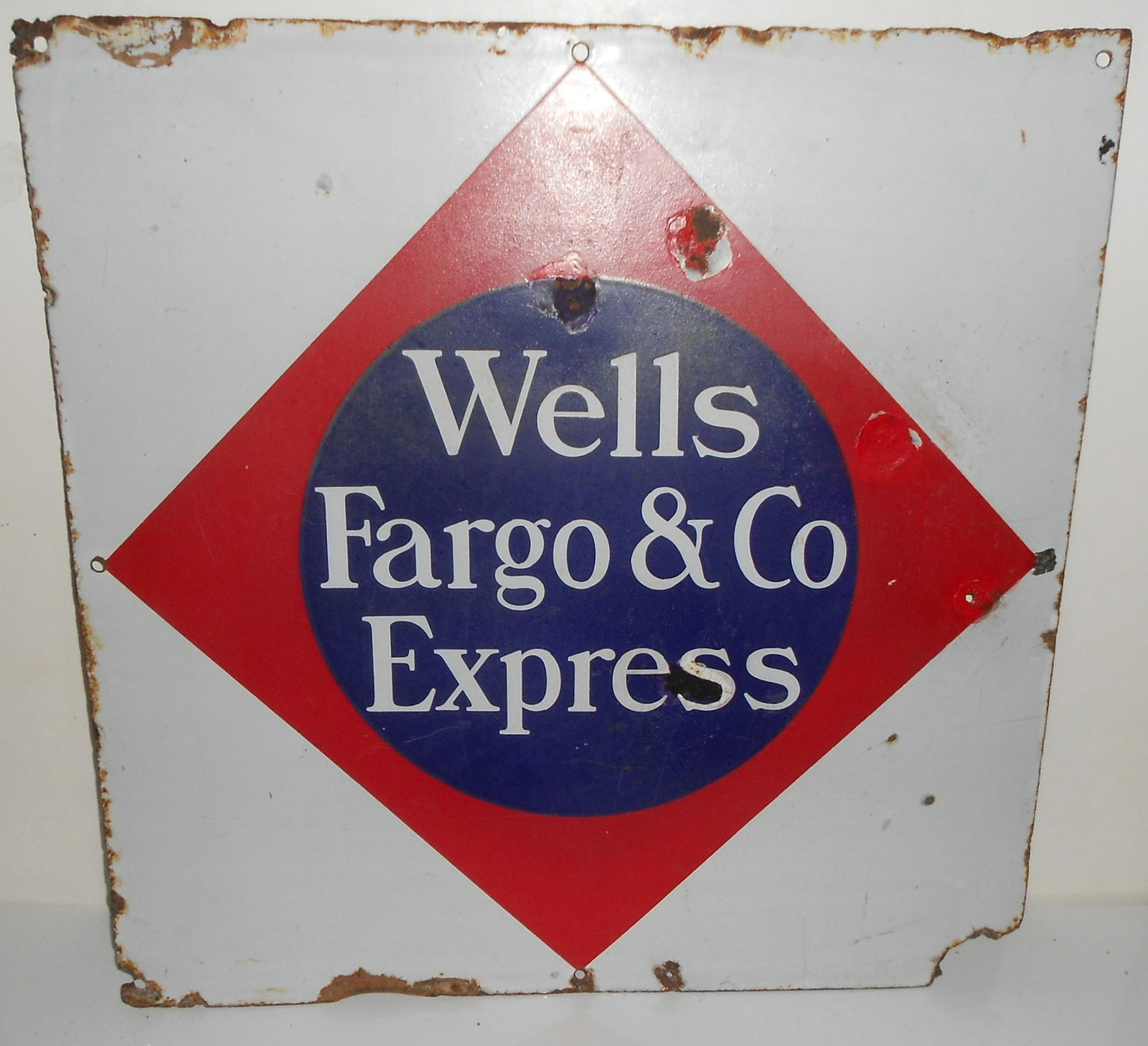 Wells Fargo Express Co. Porcelain Sign: A single sided porcelain sign made for Wells Fargo that measures 21" on each side. Severe wear to edges and a missing corner. Still graphics are very nice with touch up paint used here and there.