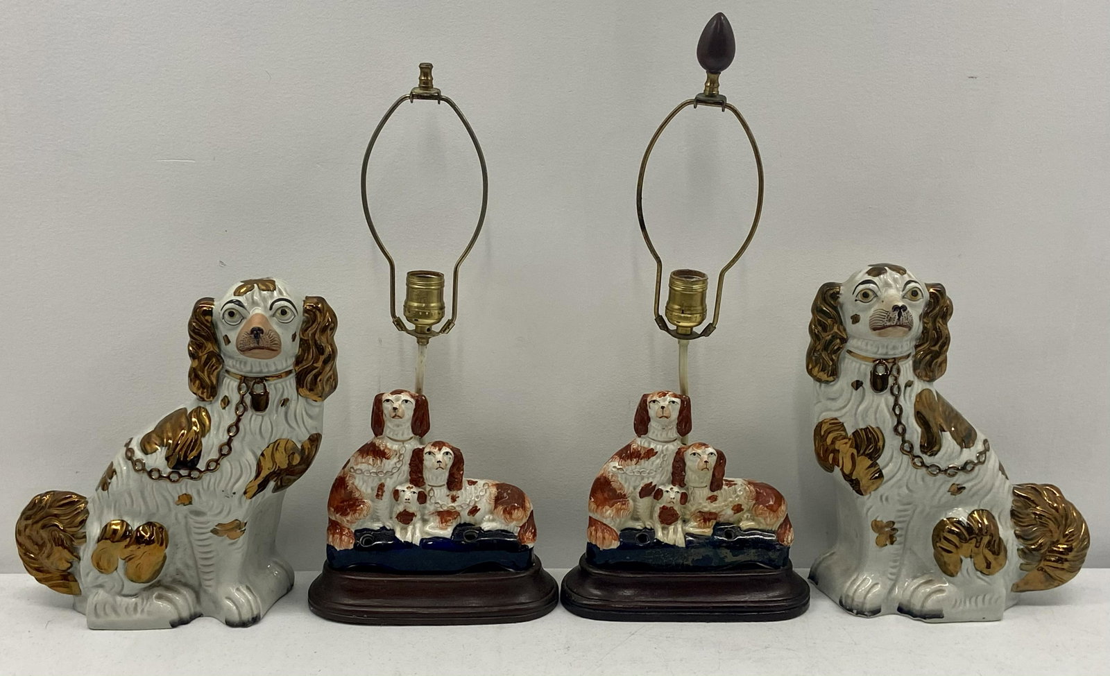 Staffordshire Dogs & Lamps: Pair of Staffordshire dogs, White w/gold trim, 11.5" h. x 10.5" w. x 3.75" d. good cond. Two electric lamps, 3 dog family, white & rust colored, w/blue, sitting on wood base, Two holes in front on blu