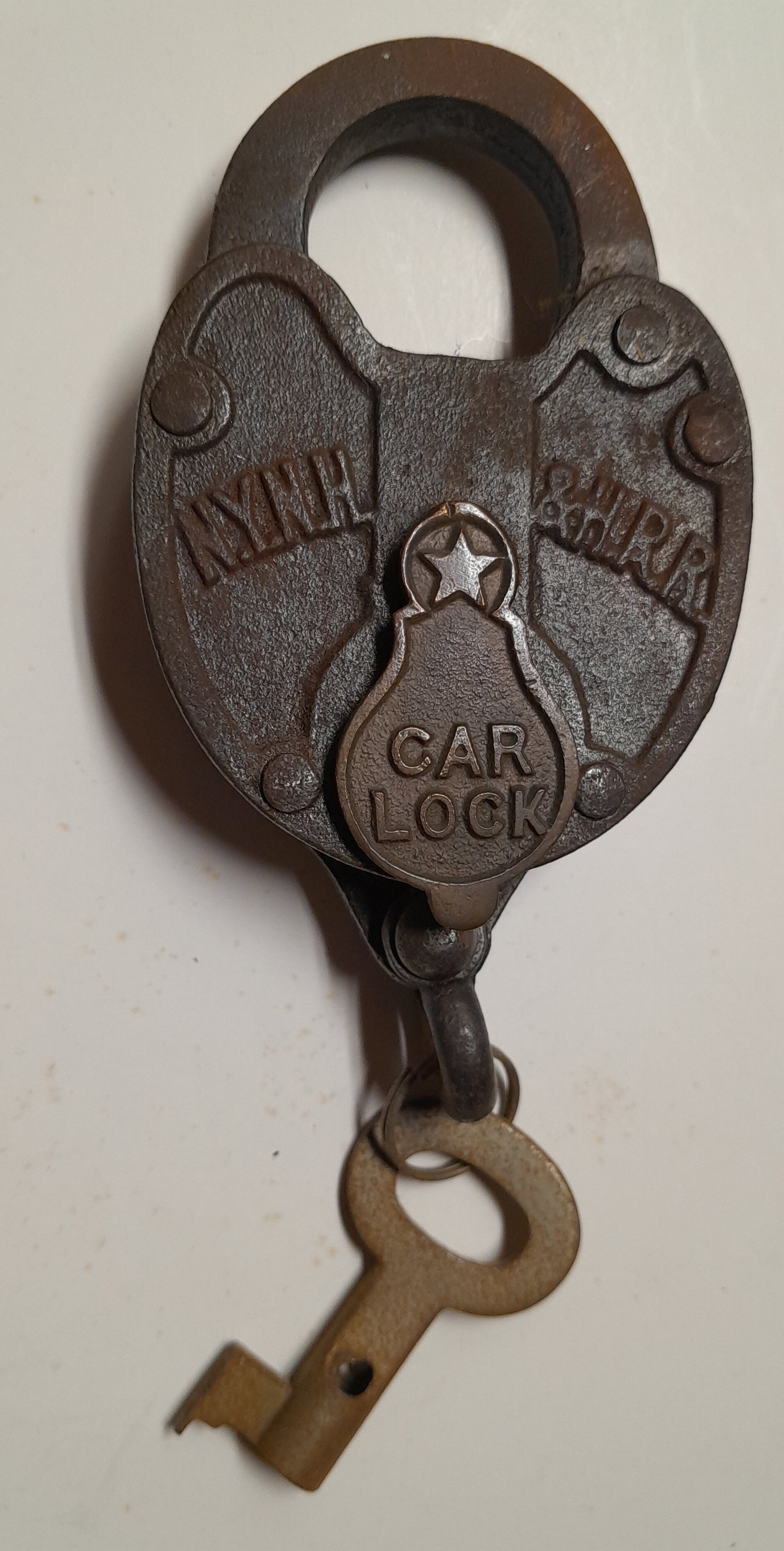 New Haven Steel Lock with Initials and CAR on Dust Cover: A standard New York New Haven and Hartford Railroad "C"ar lock. NH initials cast on front in an arc. The dust cover has CAR spelled out. This lock takes a 3 dimensional key. The one included is brass.