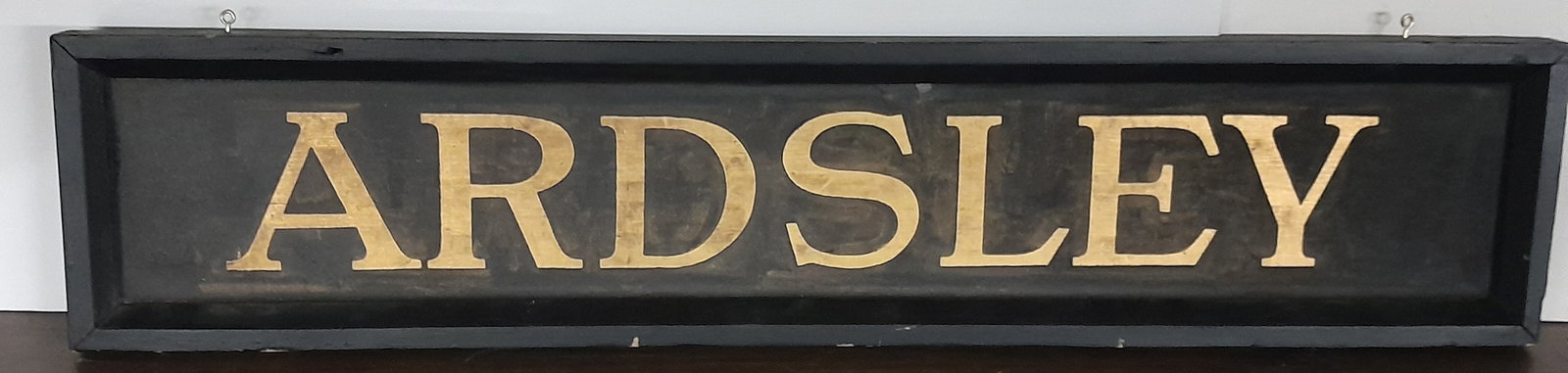 Wooden Depot Sign "ARDSLEY" 38" by 8": Nice wooden sign with beveled edge framing and a location of "Ardsley". The gold section is smooth with black "sand paint" surrounding the lettering. It has older style lettering. 2 modern hooks on to