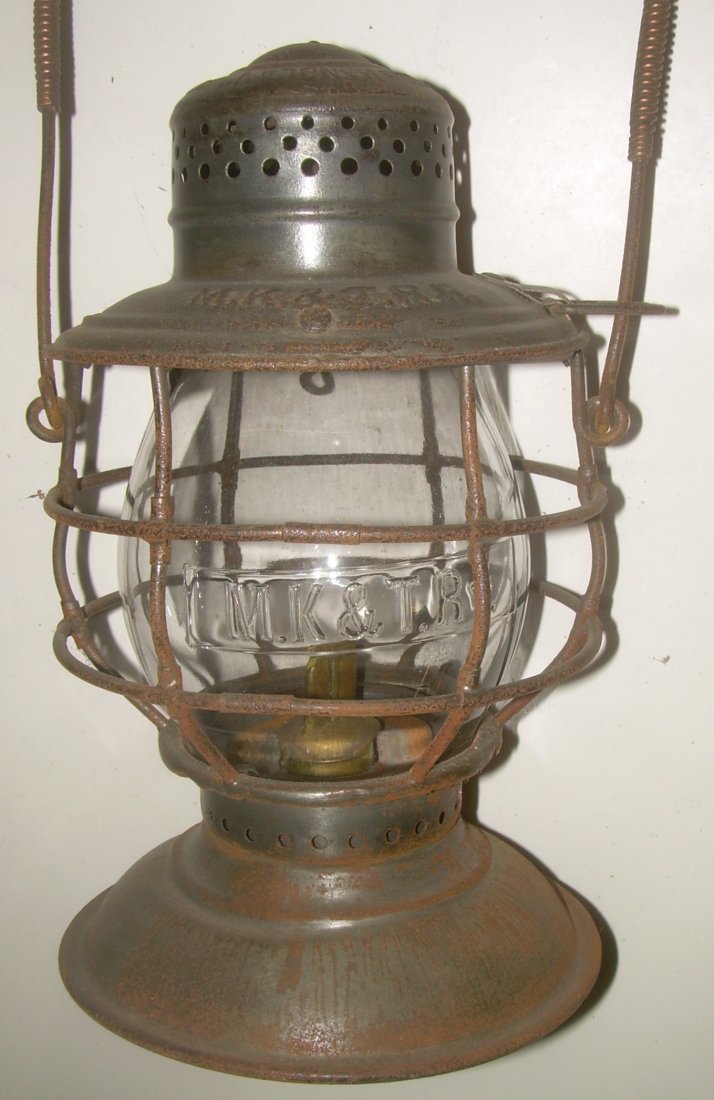 Missouri Kansas Texas RR Bellbottom Lantern: This Handlan Buck bell bottom frame is stamped MK&T RR on the lid. The lid has a bail retaining clip on one side. This is a drop in fount bellbottom. The pot is original. There is just some surface ru