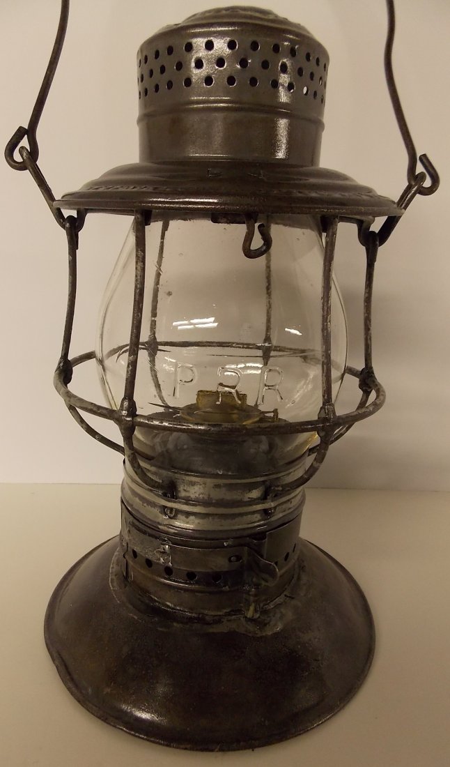 Pennsylvania Railroad Lantern Adams Bellbottom CC: An Adams & Westlake “Adams” model bellbottom frame with standard patent dates that go to 1897. The shoulder of the lid is stamped PRR in block lettering. This is not common! It has a twist off bel
