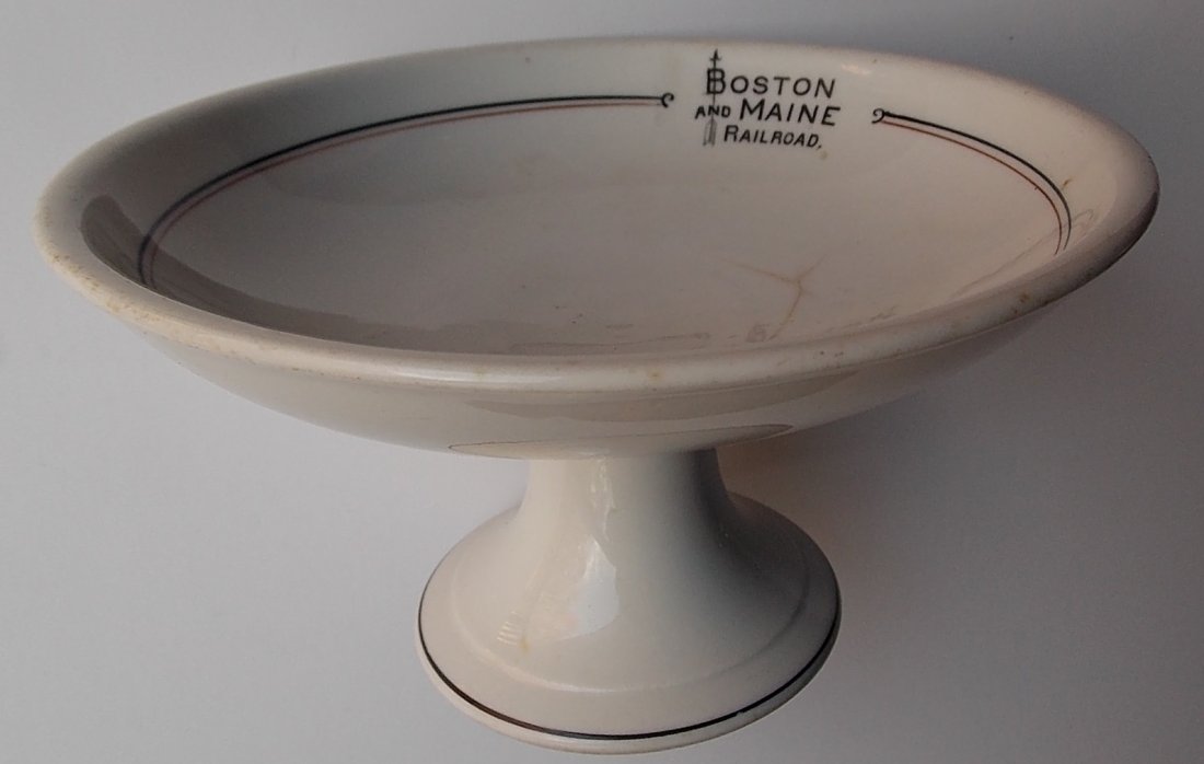 Boston & Maine China Compote “Bar Harbor” pattern: Boston & Maine Railroad china footed compote in the Bar Harbor pattern. Measures 6 1/2" wide by 3 ¾" tall. It has a 4 line crack at 1:00 in the food well. It also has a hard to see line on the bottom