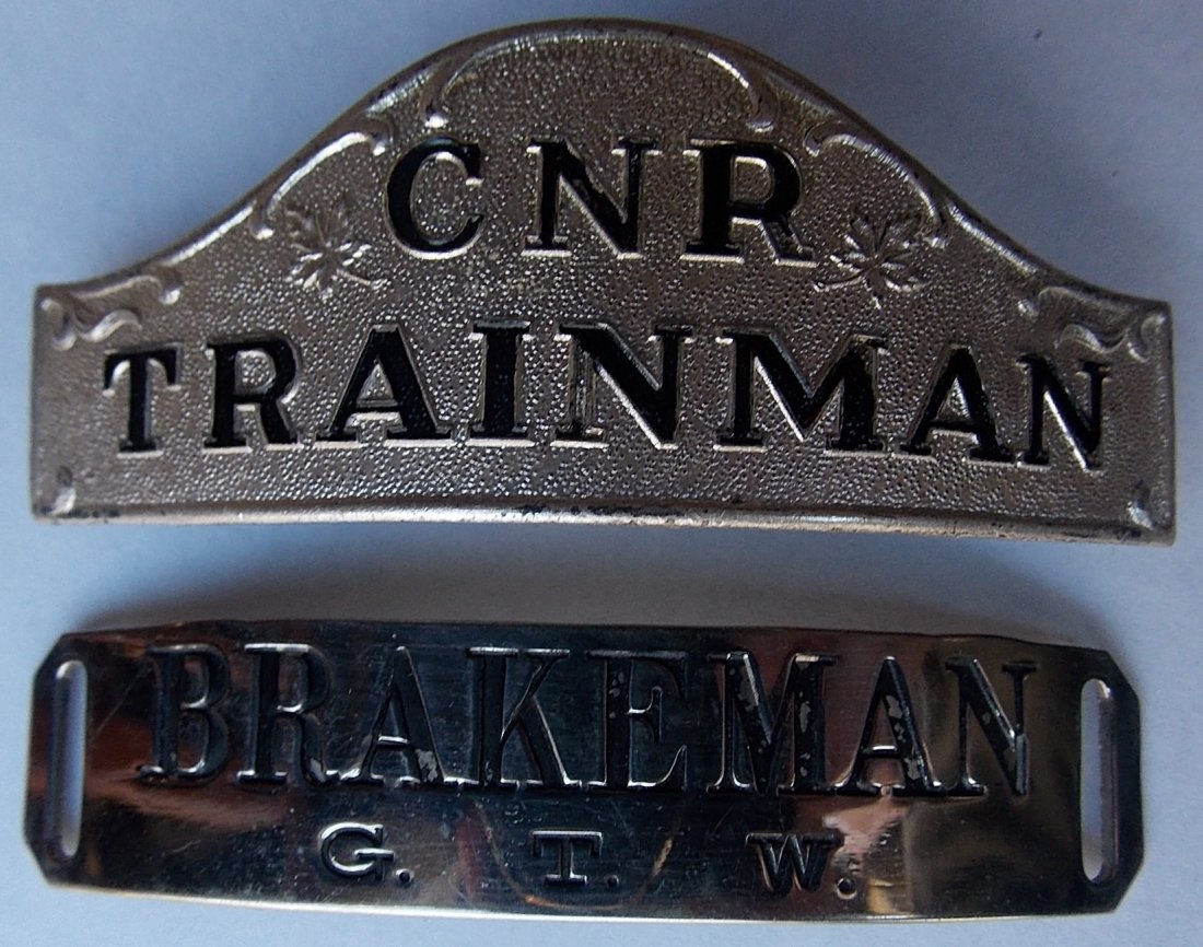 Railroad Hat Badges (2) GTW, Canadian National: A pair of railroad hat badges from Canadian based lines: (1) Grand Trunk Western Trainman – standard (2) Canadian National Railway Brakeman with Scully hallmark on the reverse