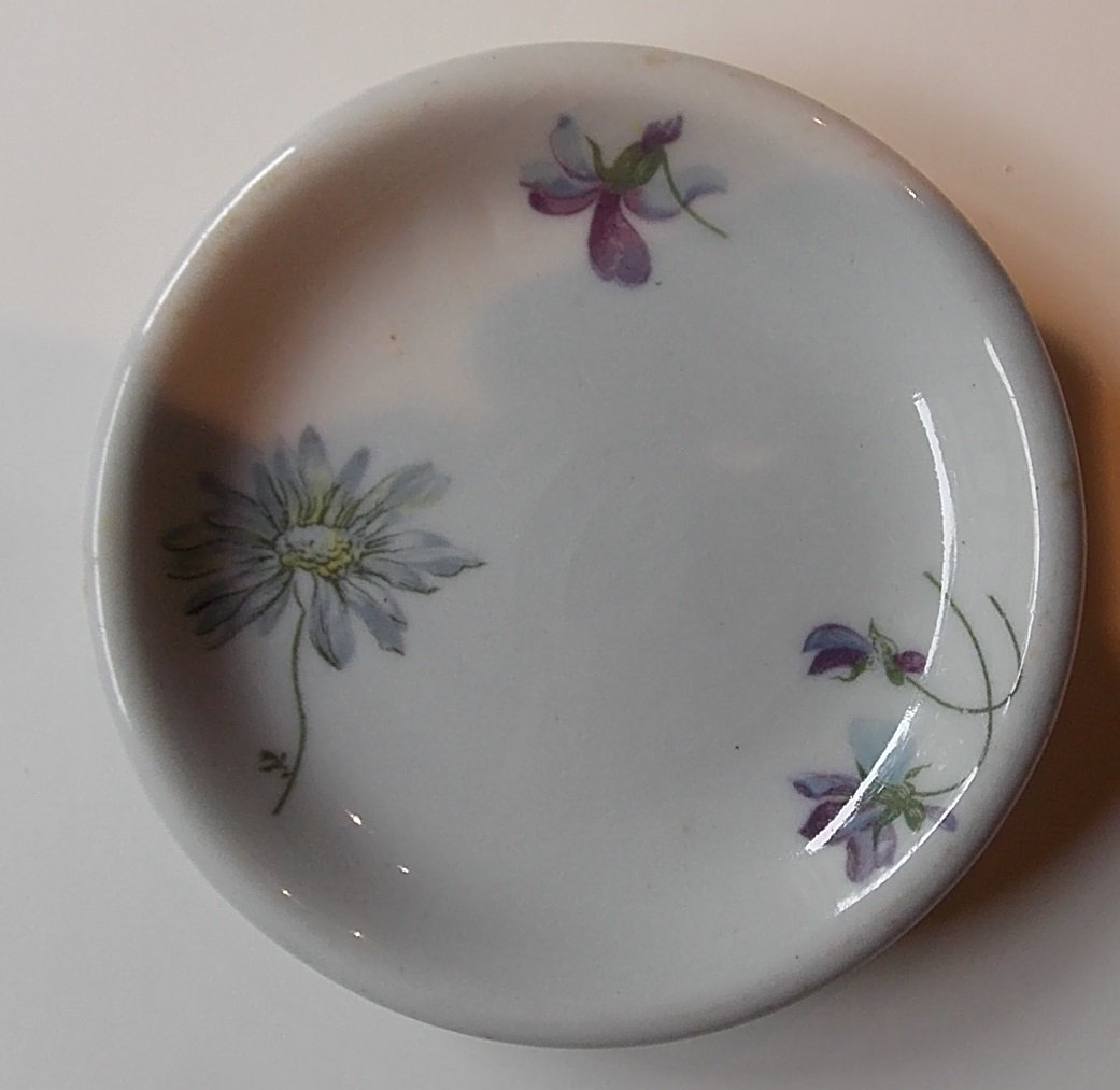 Burlington Route "Violets & Daisy" Butter Pat: A Chicago Burlington & Quincy Railroad butter pat. It measures almost 3 1/2" in diameter This is has a green Buffalo Pottery backstamp. It has light scratches in the food well. We are offering several