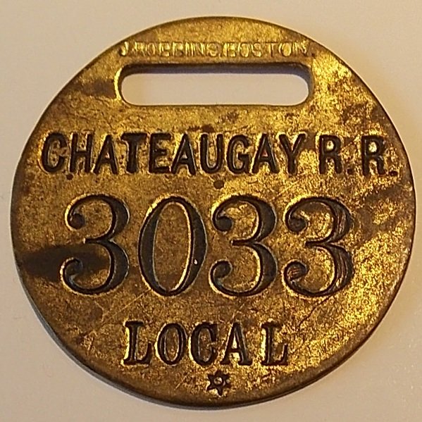 Chateaugay Railroad Narrow Gauge Baggage Tag: A 1 1/2" diameter "Local" brass baggage tag. Local means the baggage will travel just on this line and no transfer would take place beyond the Chateaugay Railroad. This was a narrow gauge line that ra
