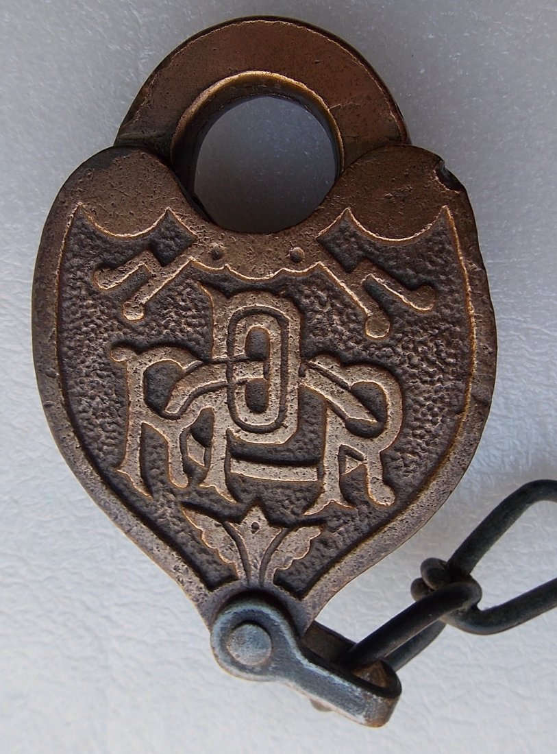 Pennsyalvania Railroad Cast Back Logo Lock: A cast back Pennsylvania Railroad Company lock made by Slaymaker. This version has the skinny tall lettering of PRR with an intertwined "CO". This lock is in great shape. It has a working dust cover s