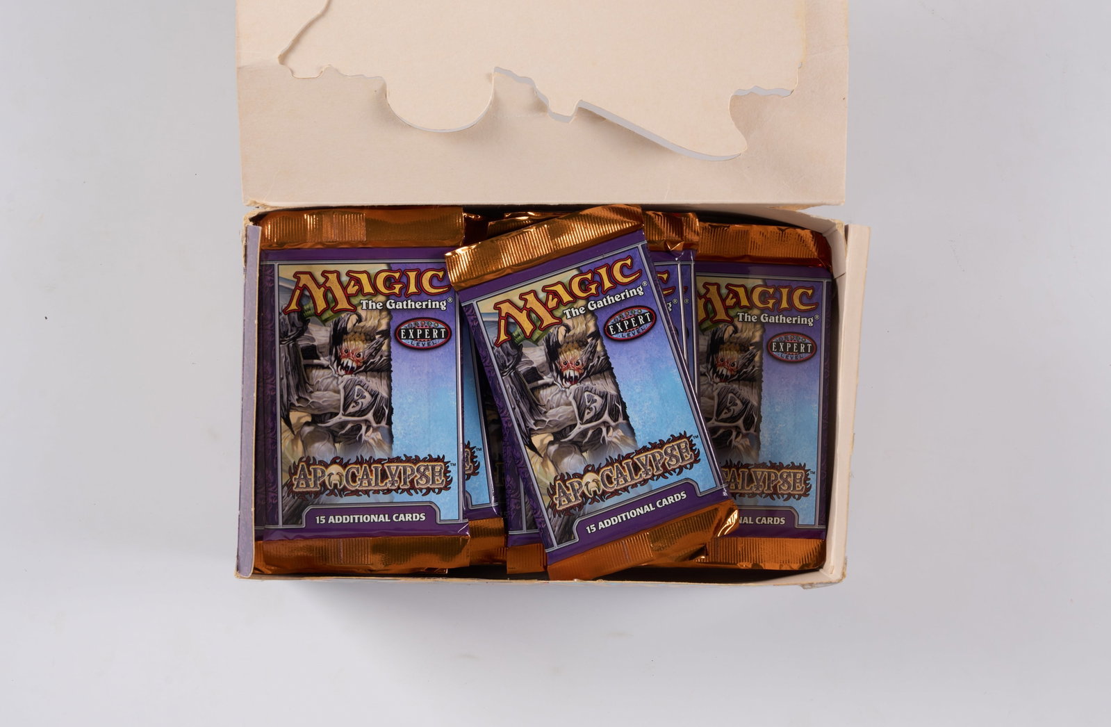 Apocalypse Booster Box - Opened (x26 Boosters): This opened booster box of Apocalypse, the twenty-third Magic: The Gathering expansion released in June 2001, contains x26 sealed booster packs in factory fresh condition. The box has rips, pen and ta
