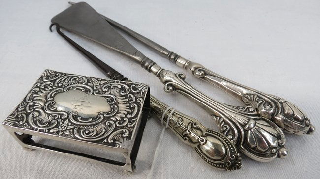 A silver matchbox holder with rococo decoration, marked: A silver matchbox holder with rococo decoration, marked Birmingham 1901, (0.5ozt) and three silver handled dressing table accessories.