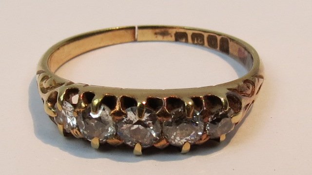 An 18ct carved head five stone half hoop: An 18ct carved head five stone half hoop diamond ring, claw set old cut stones.3g