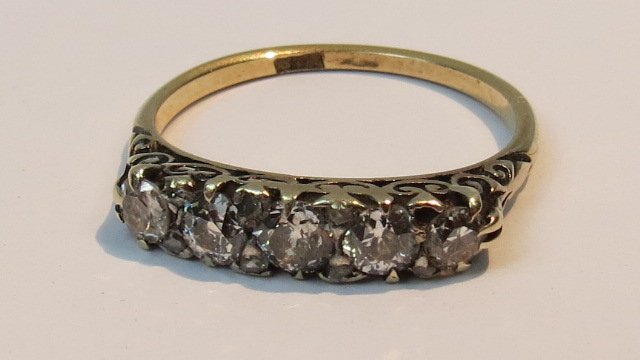 A carved head five stone half hoop diamo: A carved head five stone half hoop diamond ring, claw set old cut stones, indistinct mark on shank. 2g