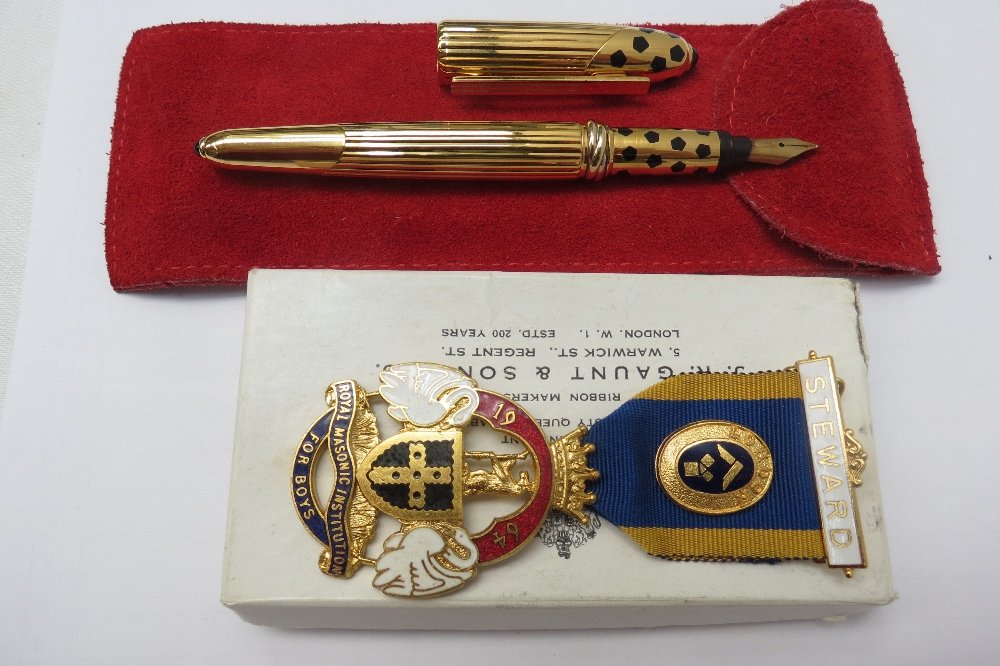 A Panthere de Cartier gold plated fountain pen circa: A Panthere de Cartier gold plated fountain pen circa 1990, with a ribbed body and black pentagons to the cap, with red soft leather slip case and a cleaning cloth together with a Masonic jewel.