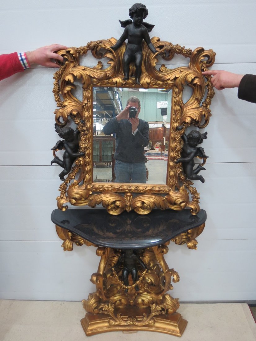 A fine quality profusely carved, pierced and gilded: A fine quality profusely carved, pierced and gilded Continental Empire style console table, the base with Serpentine fronted marble shelf with matching bevel edged over mirror, decorated with floral s