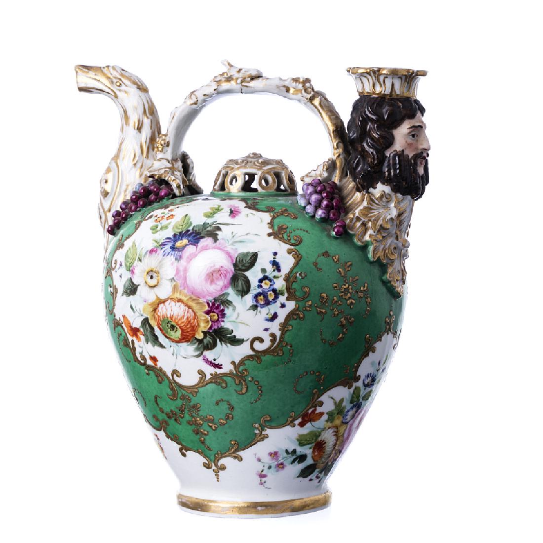 Cruse in Jacob Petit porcelain: French moulded porcelain, 19th century, a relieved polychrome and gold decoration, reserves with flowers, figurative spouts, marked JP. A slight hairline on one spout. Dim.: 23 cm.