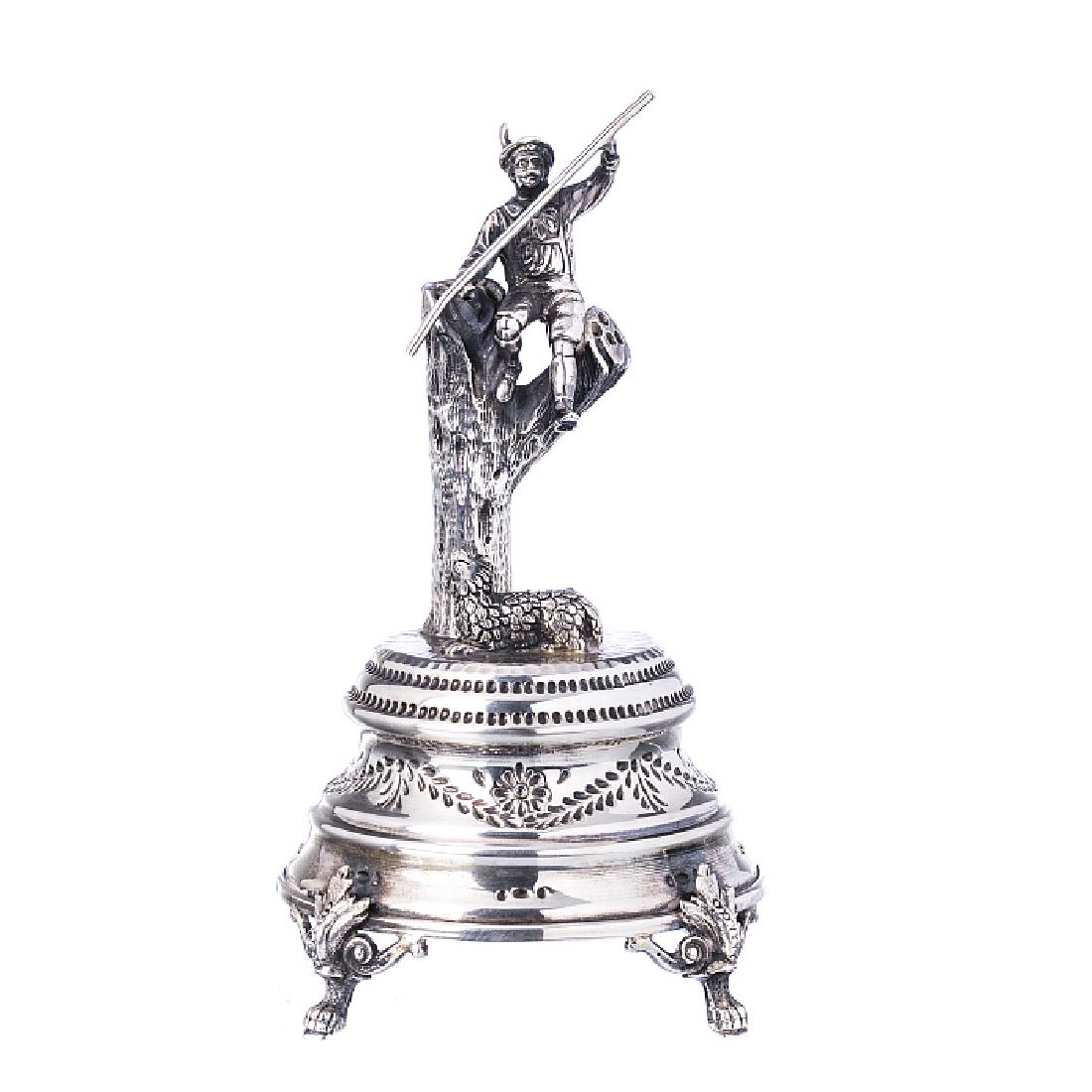 Shepherd toothpick holder in silver: Portuguese silver, an 835 eagle assay marking (post 1985), a chiselled decoration with a shepherd on a log and a sheep, a round base with claw-like feet. Approx. weight: 220 g. Dim.: 17 cm.