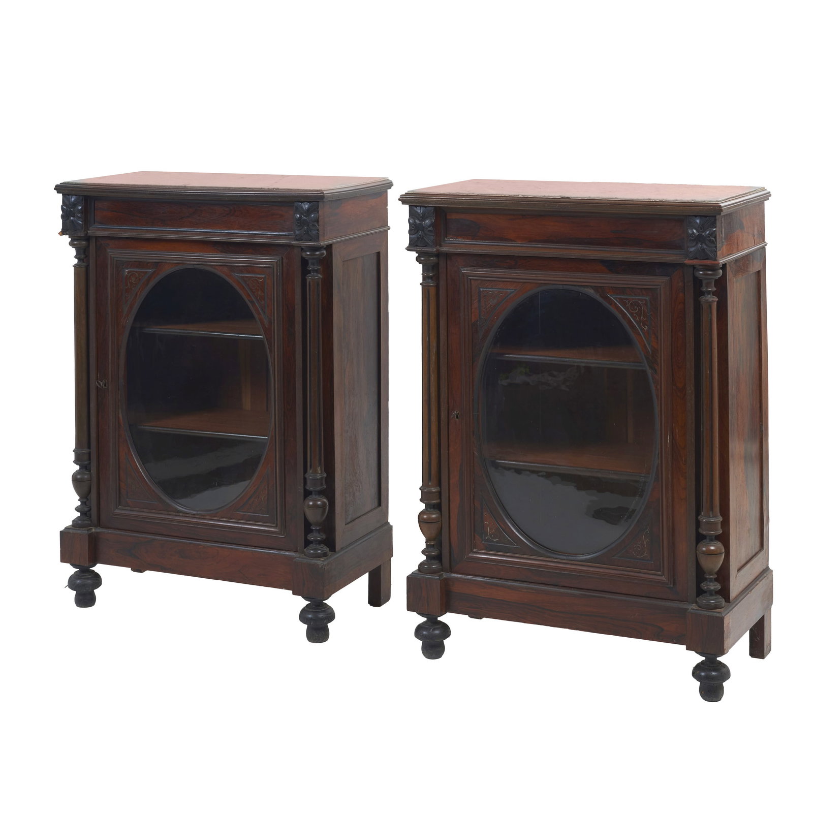 Pair of Romantic-style display cabinets: Portugal, 19th century, in laminated rosewood and other woods, with a marble top; turned side columns; carved decoration featuring floral motifs; interior with shelves; glass-panelled doors. Signs of