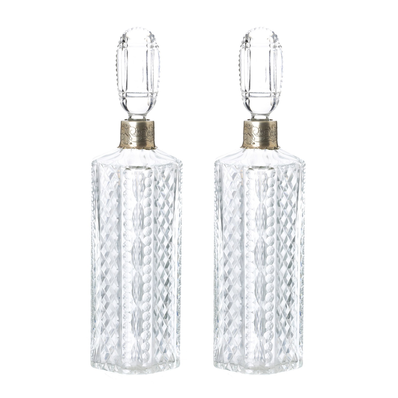 Pair of crystal and silver bottles: Portugal, c.1960, in cut crystal with silver applications, eagle hallmark 833 (1938-1984), goldsmith's mark, with incised decoration of flowers, scrolls and acanthus leaves. Signs of use, damaged lids