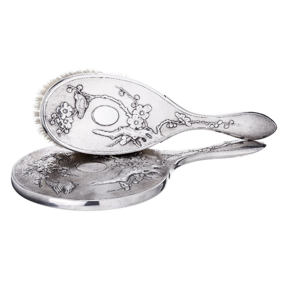 HUNG CHONG - hand mirror and brush in silver: China 19/20th Century, silver marked, 'HC', birds and plant decoration in relief. Dim:. 27cm.
