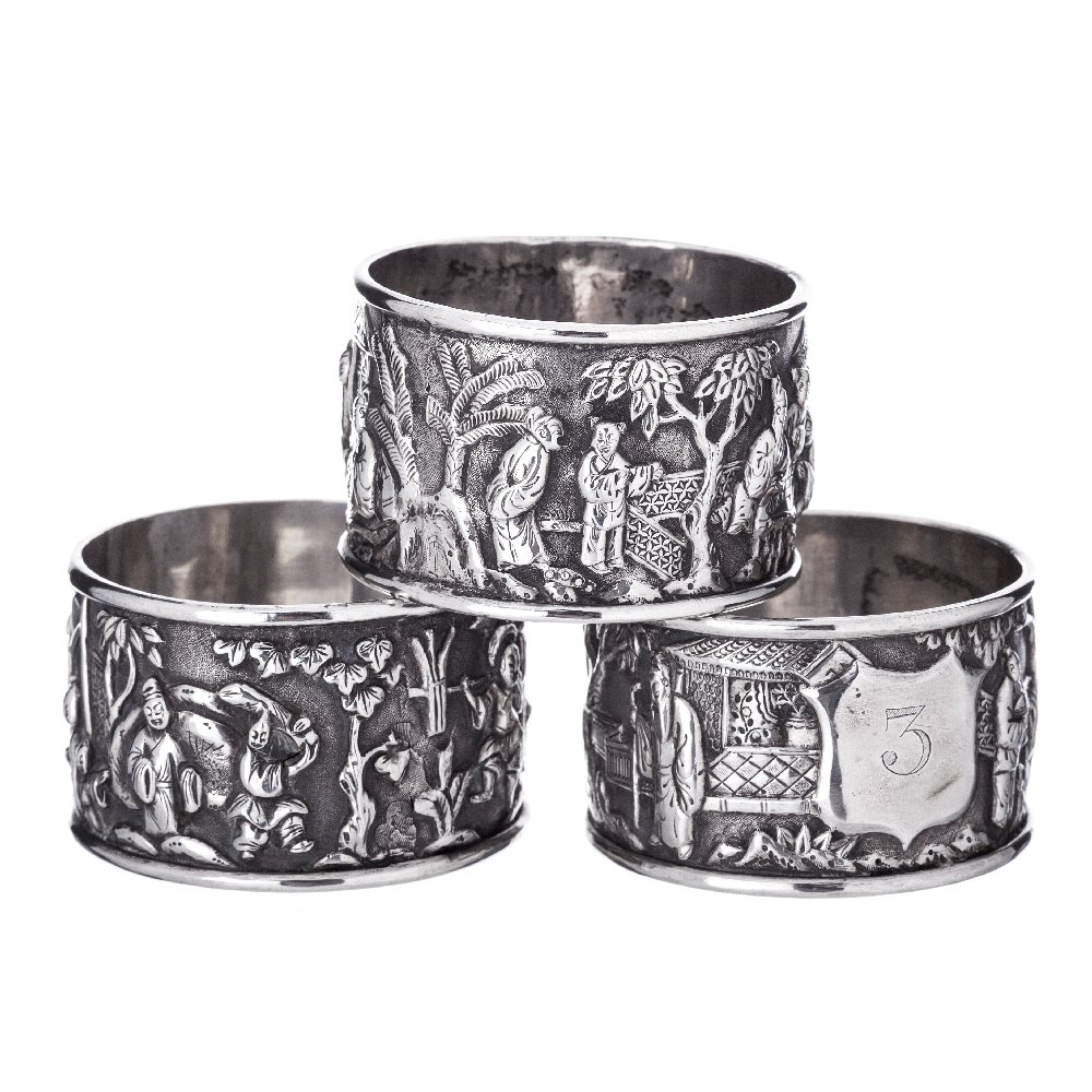 Three napkin rings in the Chinese silver: Chinese silver 19th Century, marked 'KC', decorated in relief with figures in landscape, with palette numerals (1, 2, 3) in each ring. Approx:. 85grs. Dim:. 4.8 grs.