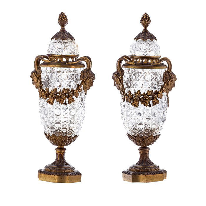 Pair of perfume sprinklers in crystal and bronze: France, c. 1900, pair of amphoras in lapidated crystal, monture in gilded bronze with faun heads and grape and vine garlands. Slight defect at the monture in bronze. Dim.:32cm.