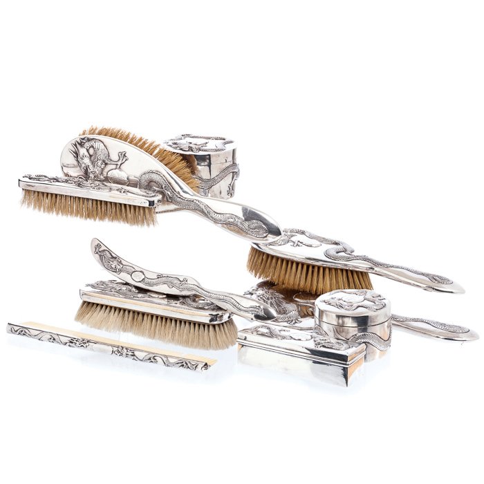 MAN HING - Toiletry set with 'dragons' in Chinese: China, Macau, 19th century, silver, marked 'MH 90', made up of a hand mirror, five brushes, three boxes and a comb with ivory teeth, relieved decoration with dragons, reserves with a monogram. Total a