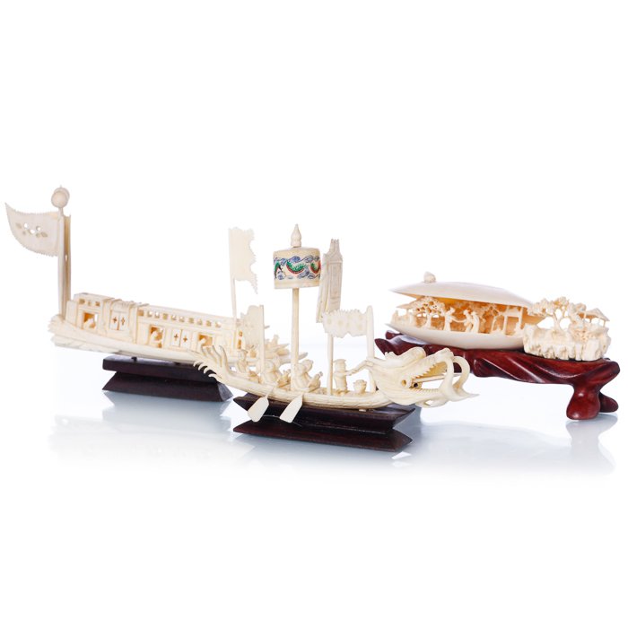 Two boats and a clam in Chinese ivory: Two boats and a clam in Chinese ivory China, 20th century, Minguo period, three sculptures in carved ivory representing two boats with figures and a clam with a village and figures, bases in carved wo