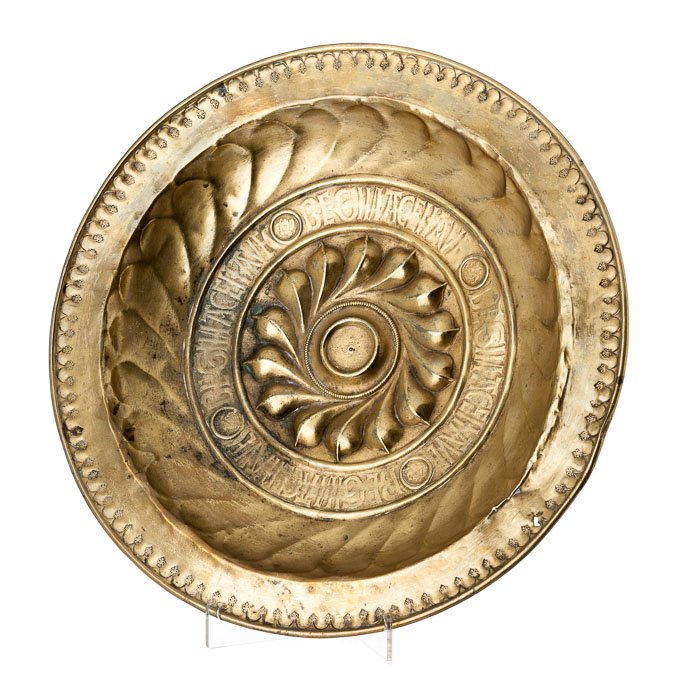 Nuremberg alms plate: Hanging plate in brass, 16th century, border with incised fleur-de-lis decoration, lobed interior and gothic characters inscription. Signs of wear. Dim.:39,5cm.