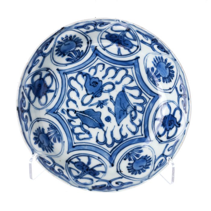 Small saucer in Chinese porcelain, Wanli: Chinese porcelain, Ming Dynasty, Wanli period (1563-1620), blue decoration of reserves with flowers and Taoist symbols. Hairline at the centre. Dim.: 14.5 cm.