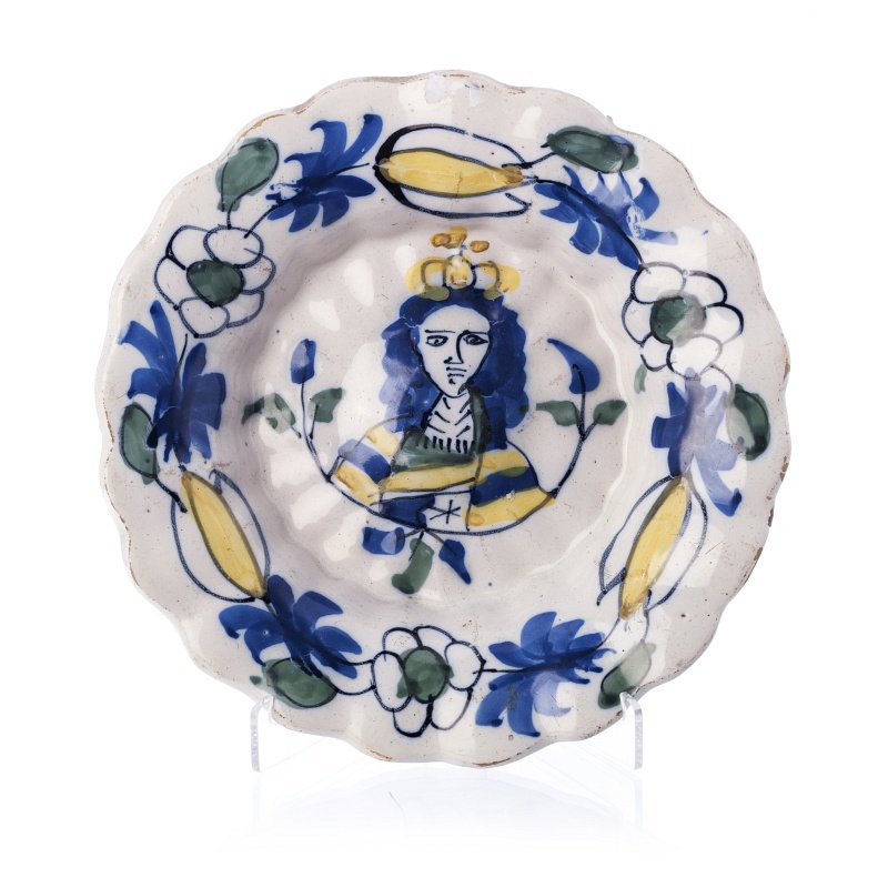 Plate in Delft faience, portrait of William of Ora: Netherlands, 17th century, Delft faience, lobed, polychrome decoration with portrait of King William of Orange. Mark on the back. Signs of wear. Dim.:22cm.