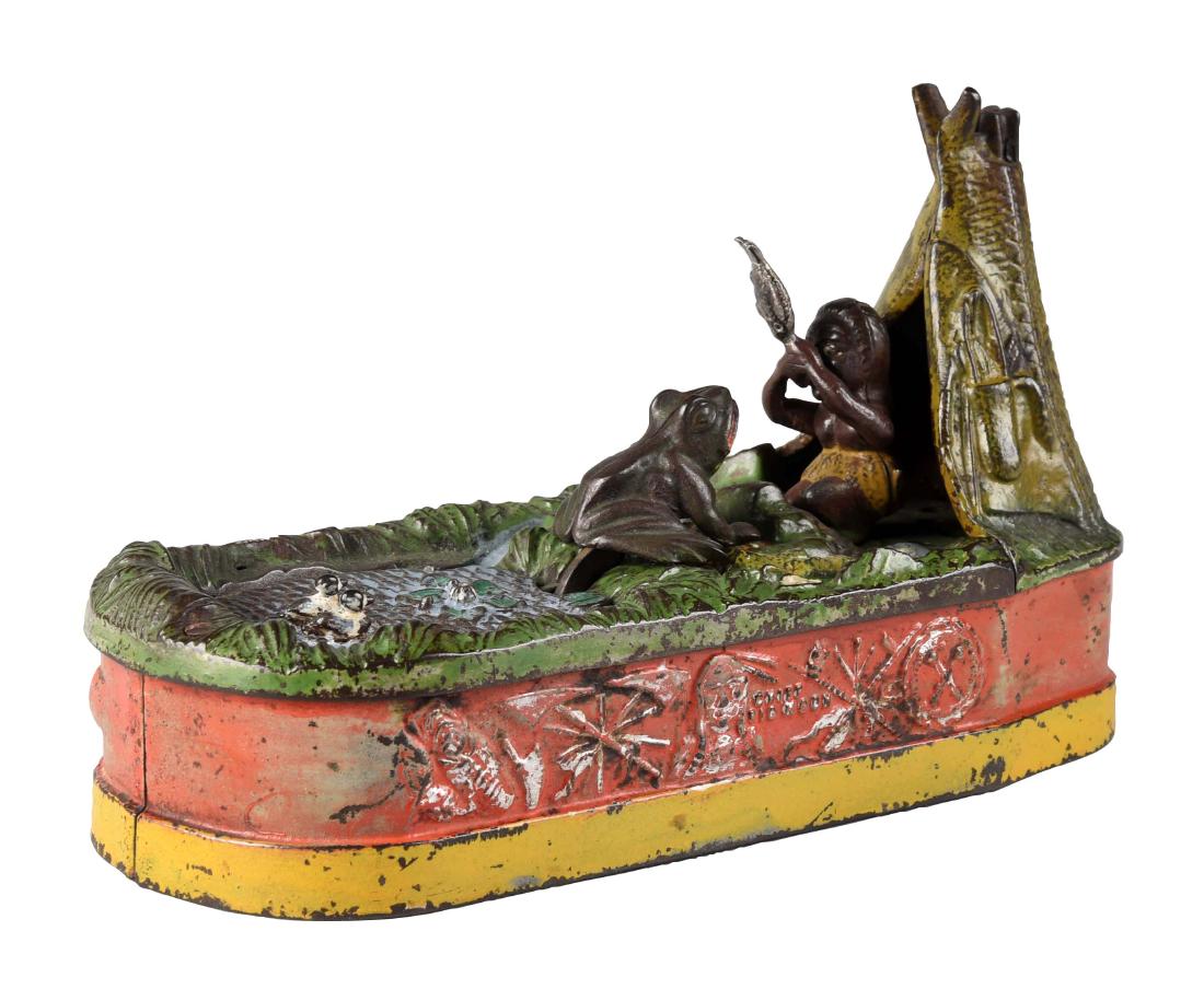 J. & E. Stevens Cast Iron Chief Big Moon Mechanical: Place a coin in the slot in the front of the pond and press the lever. As the coin disappears a frog springs from the water after the fish that the Indian squaw has. (JY). (Very Good). 10" x 6 -1/2".