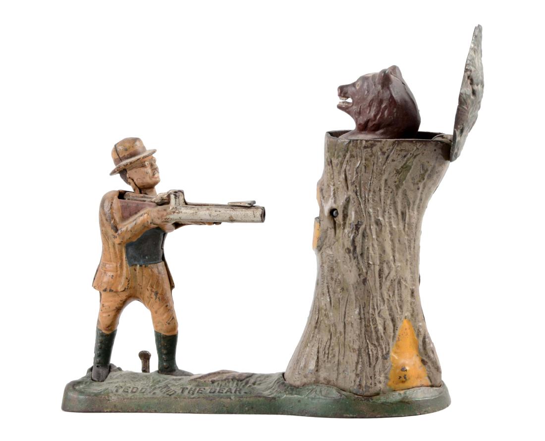 J. & E. Stevens Cast Iron Teddy & Bear Mechanical Bank.: Cock the rifle, place a coin at the base of the rifle and press the lever to fire the coin into the tree as a bear pops up. Original trap. Grey tree variation. (JY). (Very Good). 10" x 9".
