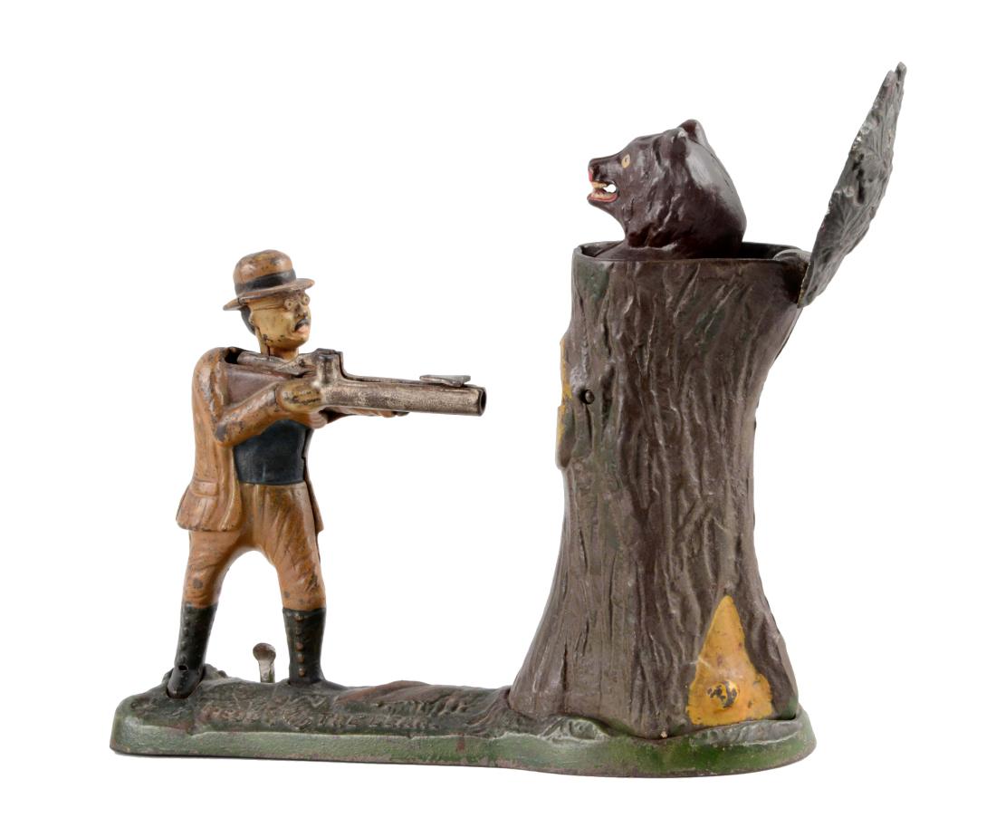 J. & E. Stevens Cast Iron Teddy & Bear Mechanical Bank.: Cock the rifle, place a coin at the base of the rifle and press the lever to fire the coin into the tree as the bear pops up. Original trap. (JY). (Very Good - Very Good Plus). 10" x 7 -1/4".