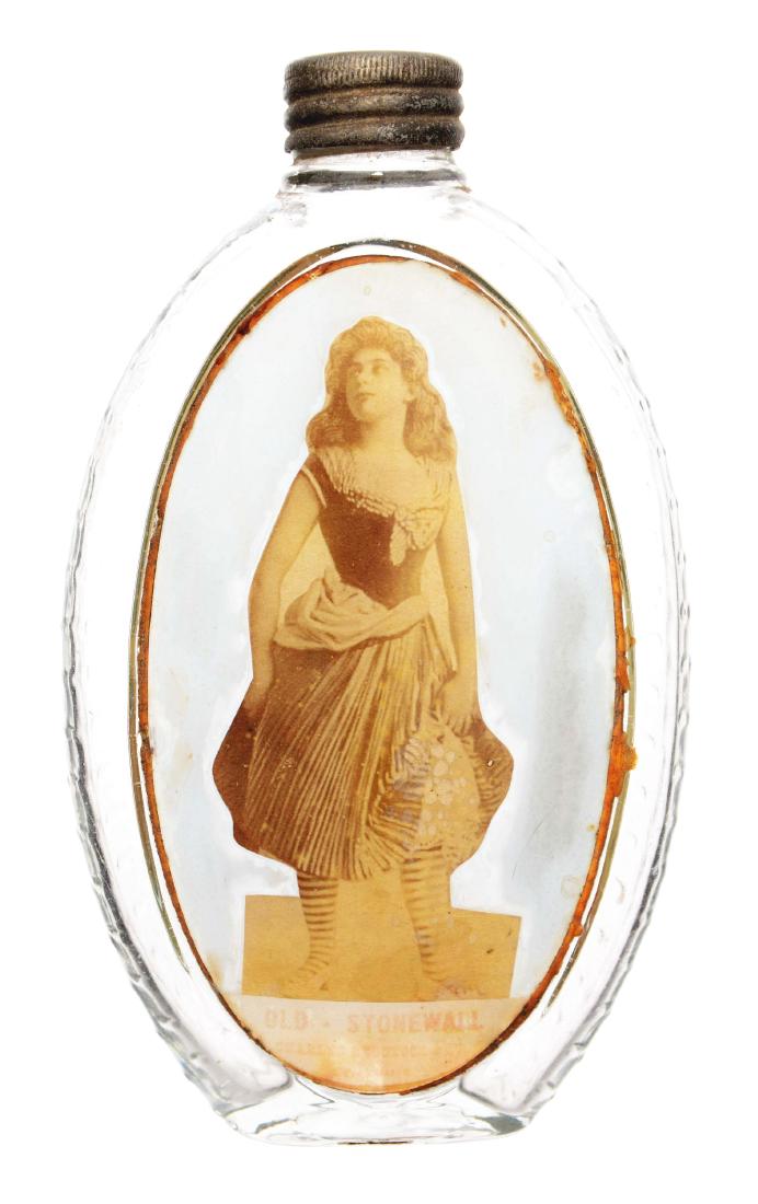 Label Under Glass Flask.: Oval glass flask with diamond textured back and label under glass of a 19th century lady in a striped dress. Dimensions: 3-1/2"W x 6"T.