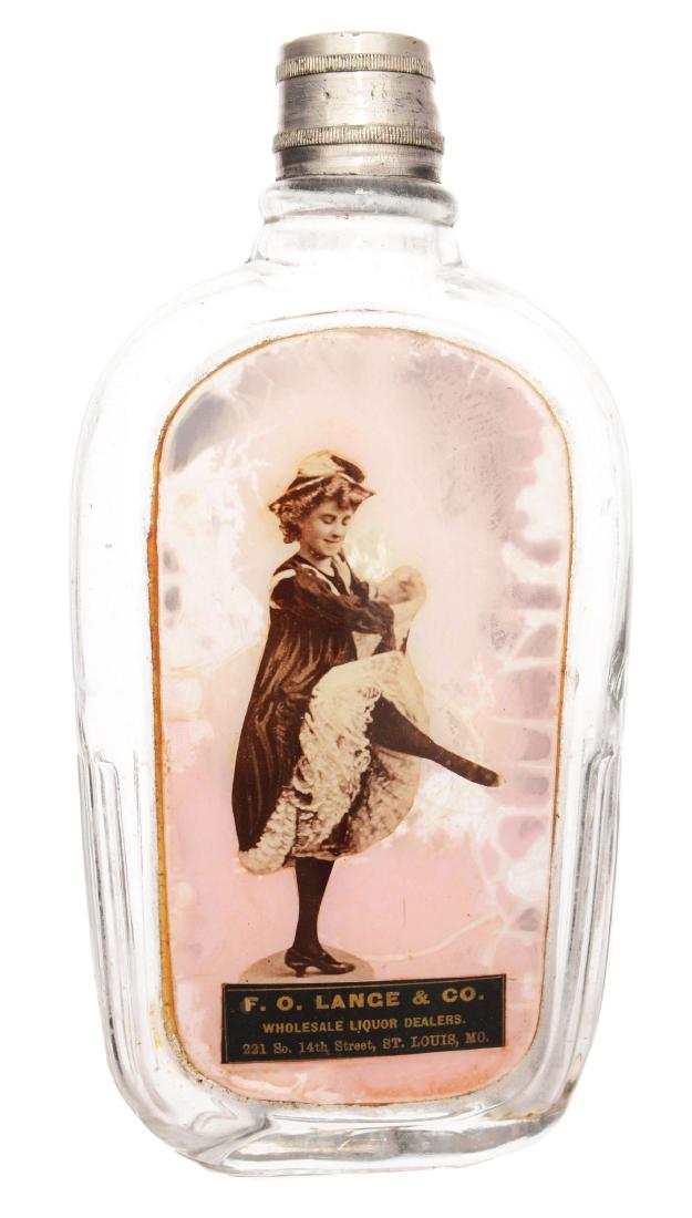 F.O. Lange & Co. Glass Flask.: Rectangular glass flask with lid and image behind glass of a dancing lady. The image reads "F.O. Lange & Co. Wholesale Liquor Dealers 221 So. 14th Street, St. Louis, MO." Dimensions: 4"W x 7-1/2"T.