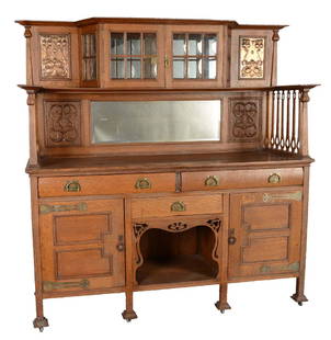 Shapland & Petter Of Barnstaple Oak Sideboard.: Quarter sawn oak sideboard crafted by Shapland & Petter of Barnstaple, England. This sideboard features beautiful carved wood detailing, copper repousse panels and mullion doors with domed glass. Insi